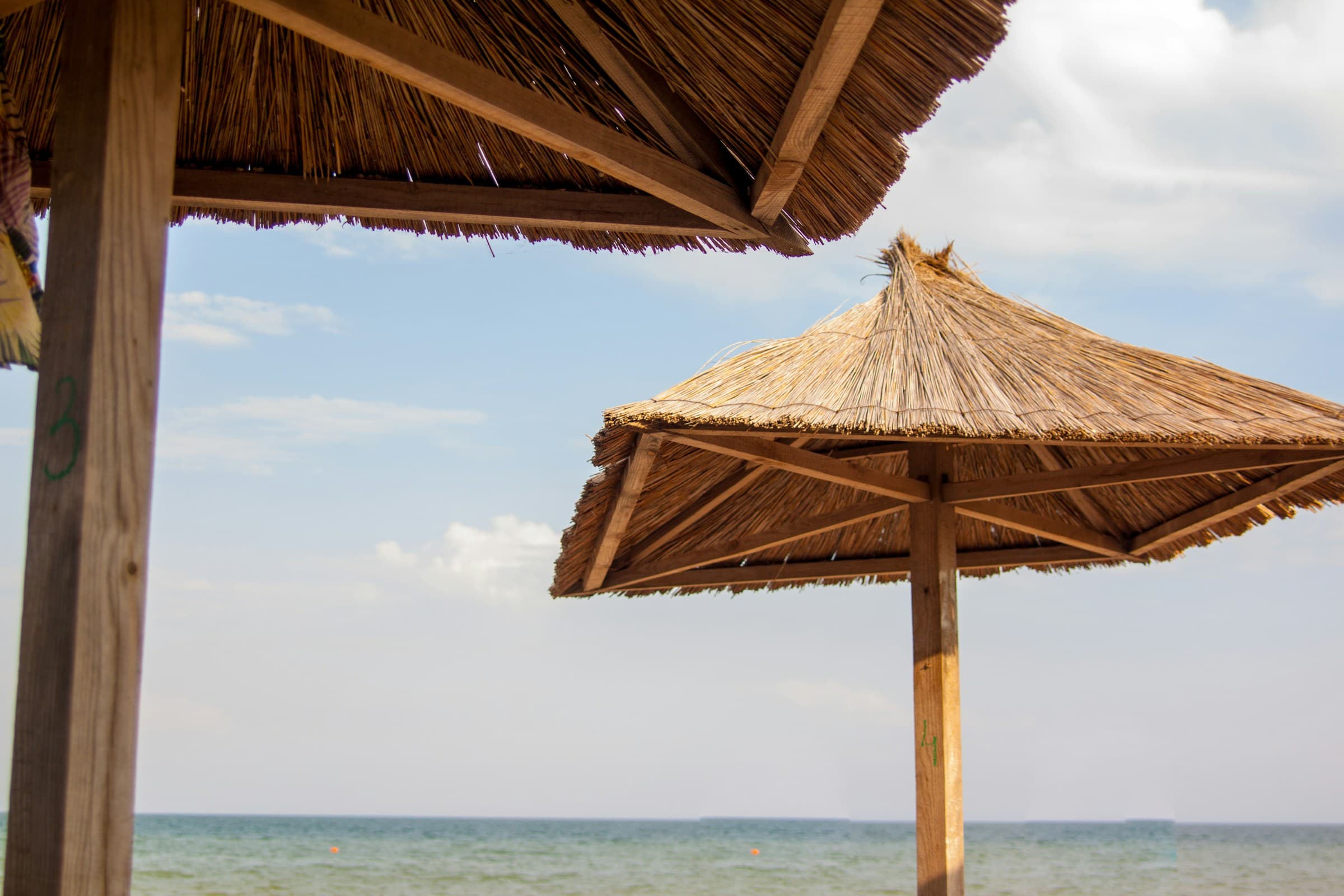 Umbrare de stuf pe plajă, marea la prânz